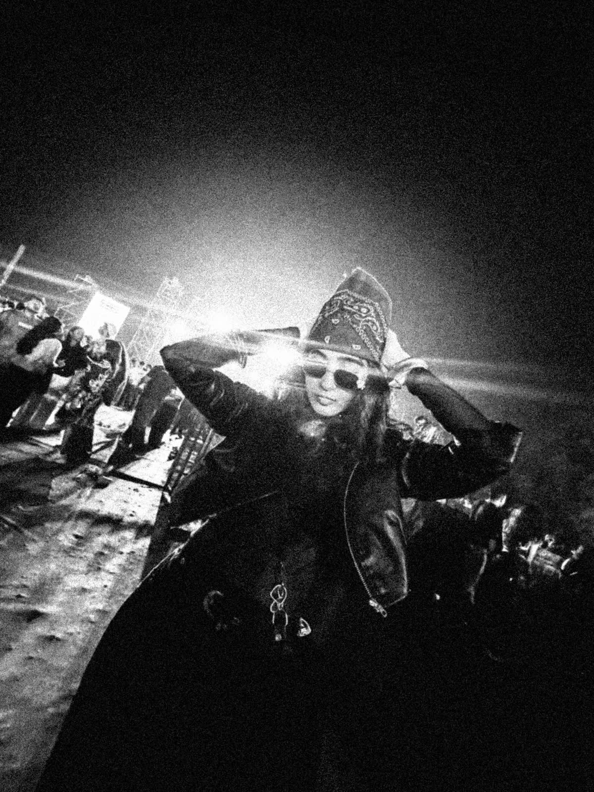 In the crowd, bandana and sunglasses lit from behind